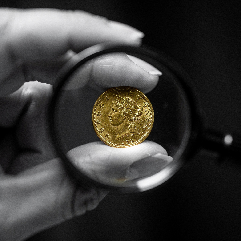 A gold coin examined through a jeweler's loupe